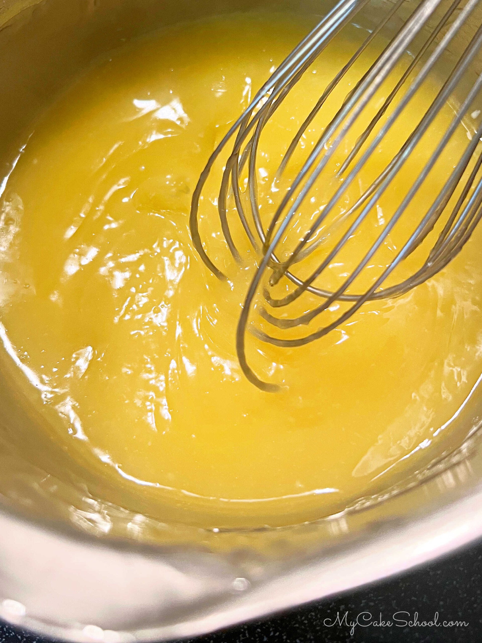 Lemon Curd in a saucepan with whisk.