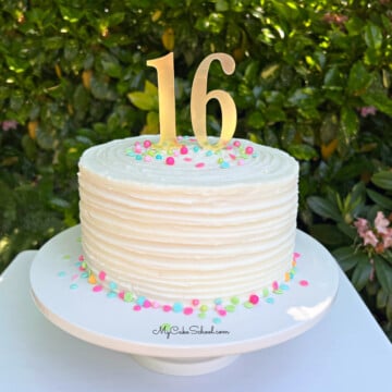 Ridged textured buttercream cake on a pedestal with sprinkles and "16" cake topper