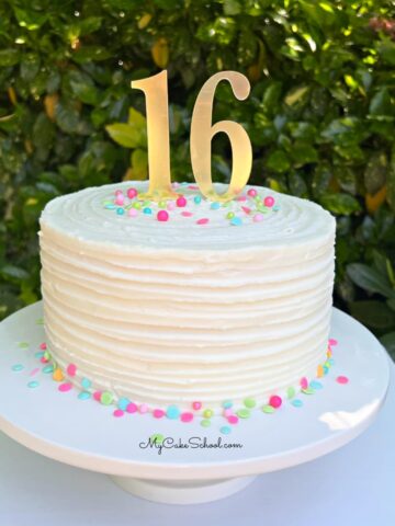 Ridged textured buttercream cake on a pedestal with sprinkles and "16" cake topper