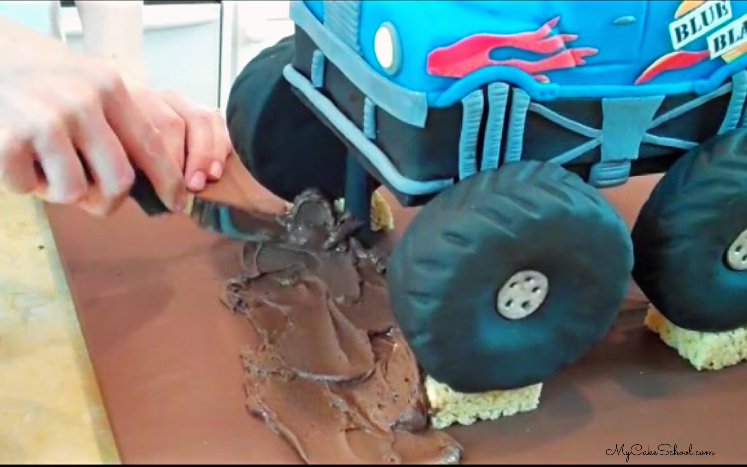 Spreading frosting around the base of the monster truck.