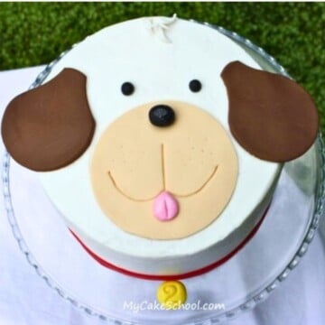 Easy Puppy Cake on a glass pedestal. Puppy face on top of a round cake.