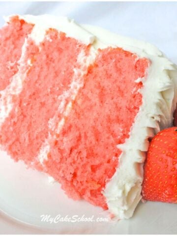 Slice of three layer strawberry cake from cake mix on a plate, next to two fresh strawberries.