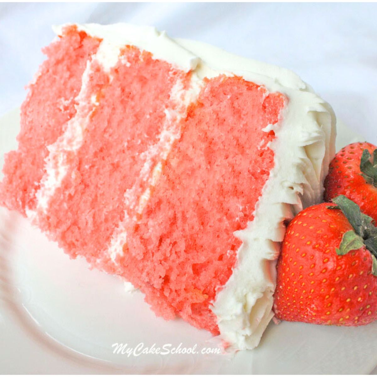 Slice of three layer strawberry cake from cake mix on a plate, next to two fresh strawberries.