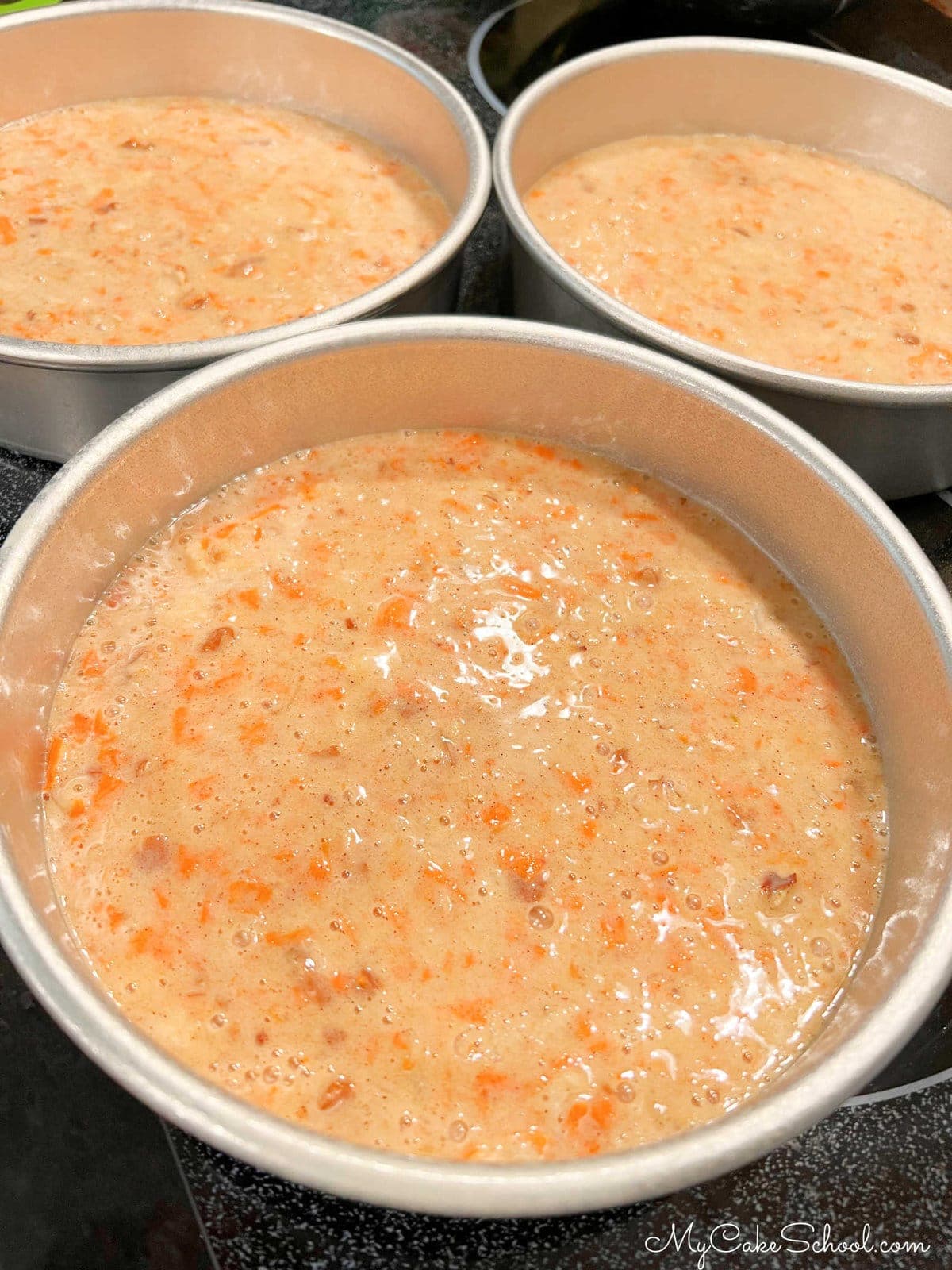 Three cake pans with carrot cake batter