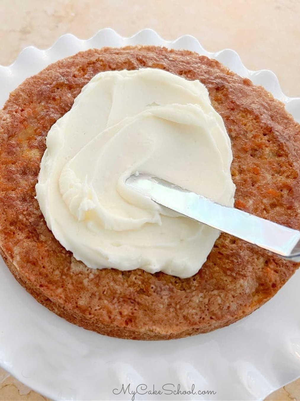 Spreading cream cheese frosting onto carrot cake layer.