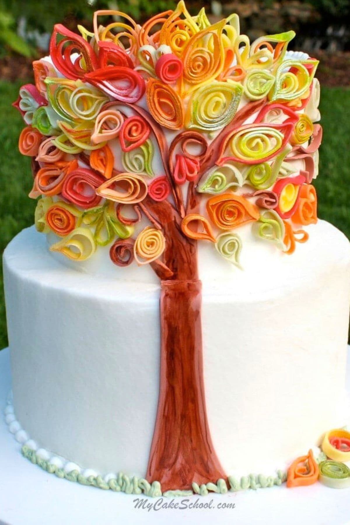 Autumn Quilling Cake on a cake plate-- a fondant tree trunk with fondant quilled colorful leaves.