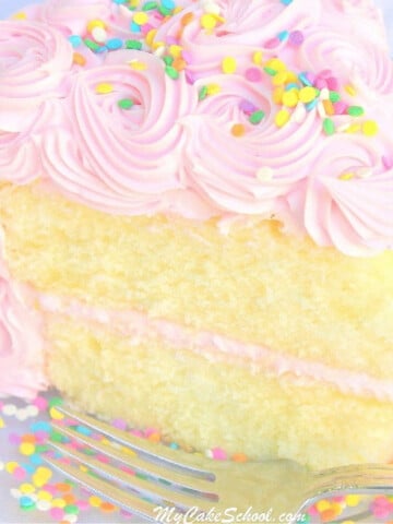 Slice of White Almond Sour Cream Cake on a plate, frosted with pink frosting.