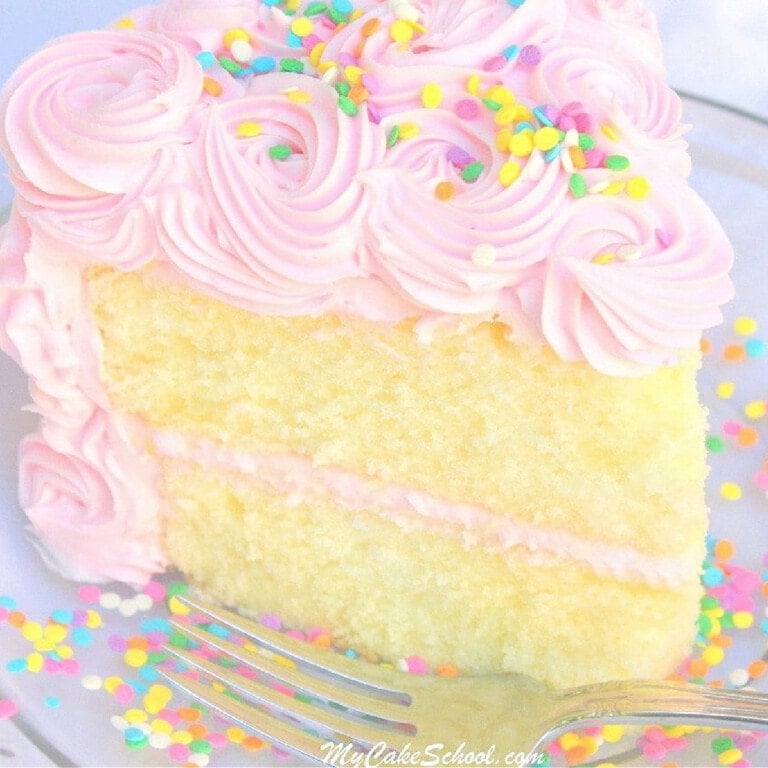 Slice of White Almond Sour Cream Cake on a plate, frosted with pink frosting.