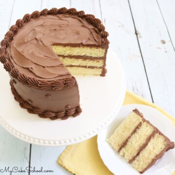 Sliced yellow cake with chocolate frosting on white pedestal with a plated slice next to it.