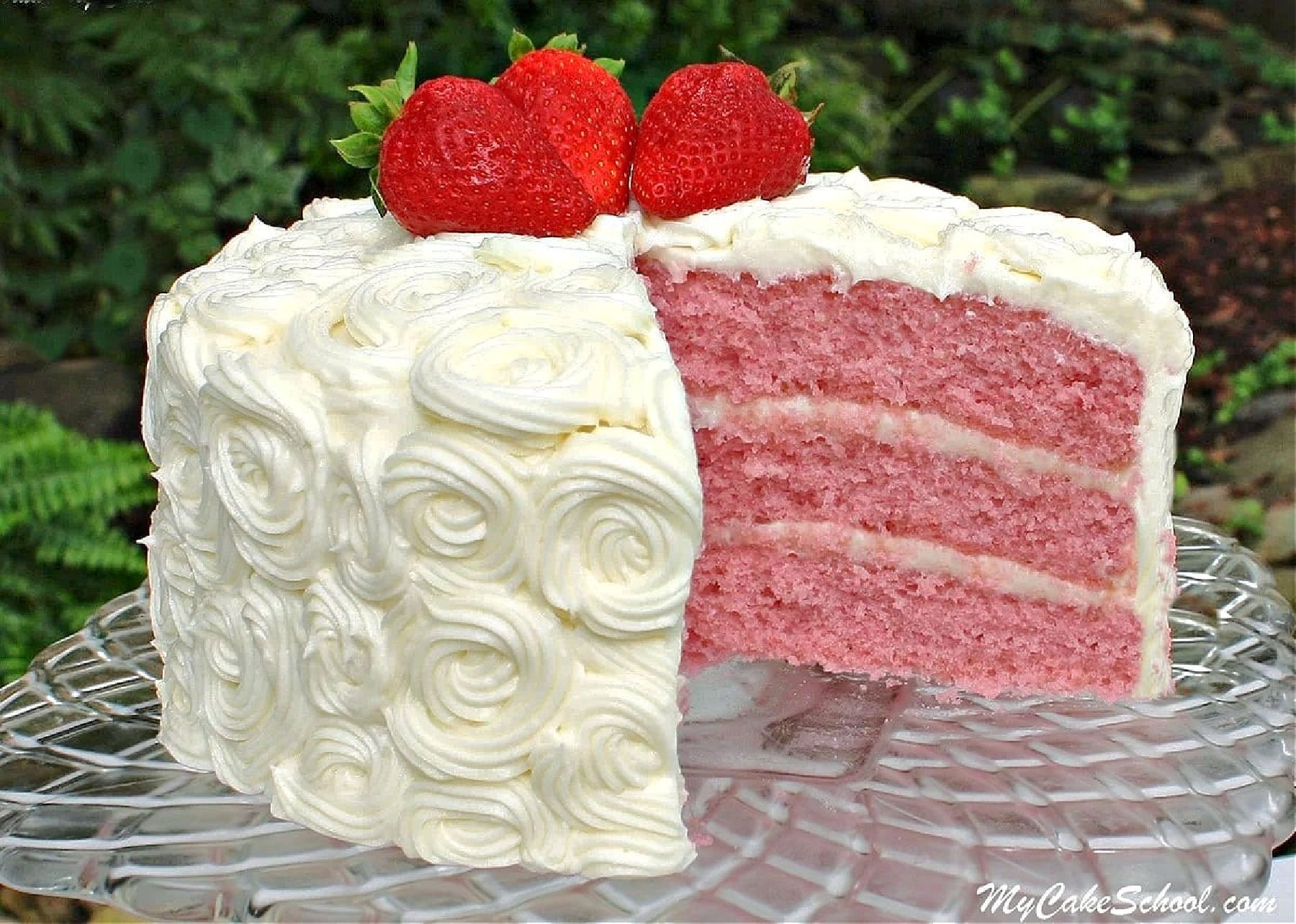 Sliced strawberry cake from scratch on a glass pedestal.