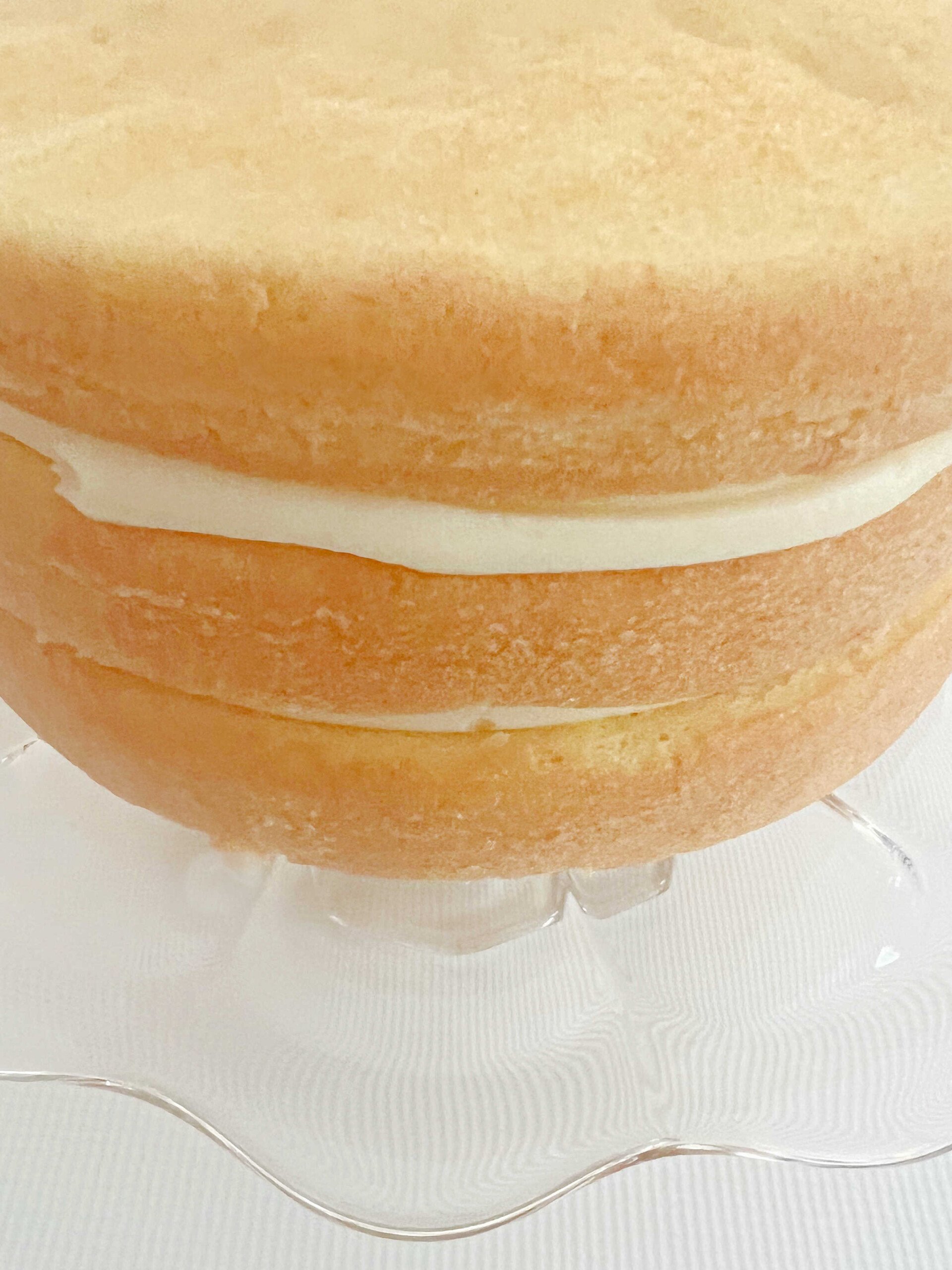 Three filled and stacked Pina Colada Cake Layers on a cake pedestal, before applying frosting.