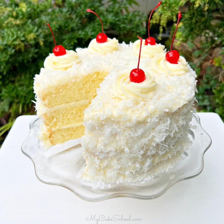 Sliced Pina Colada Cake on a glass pedestal.