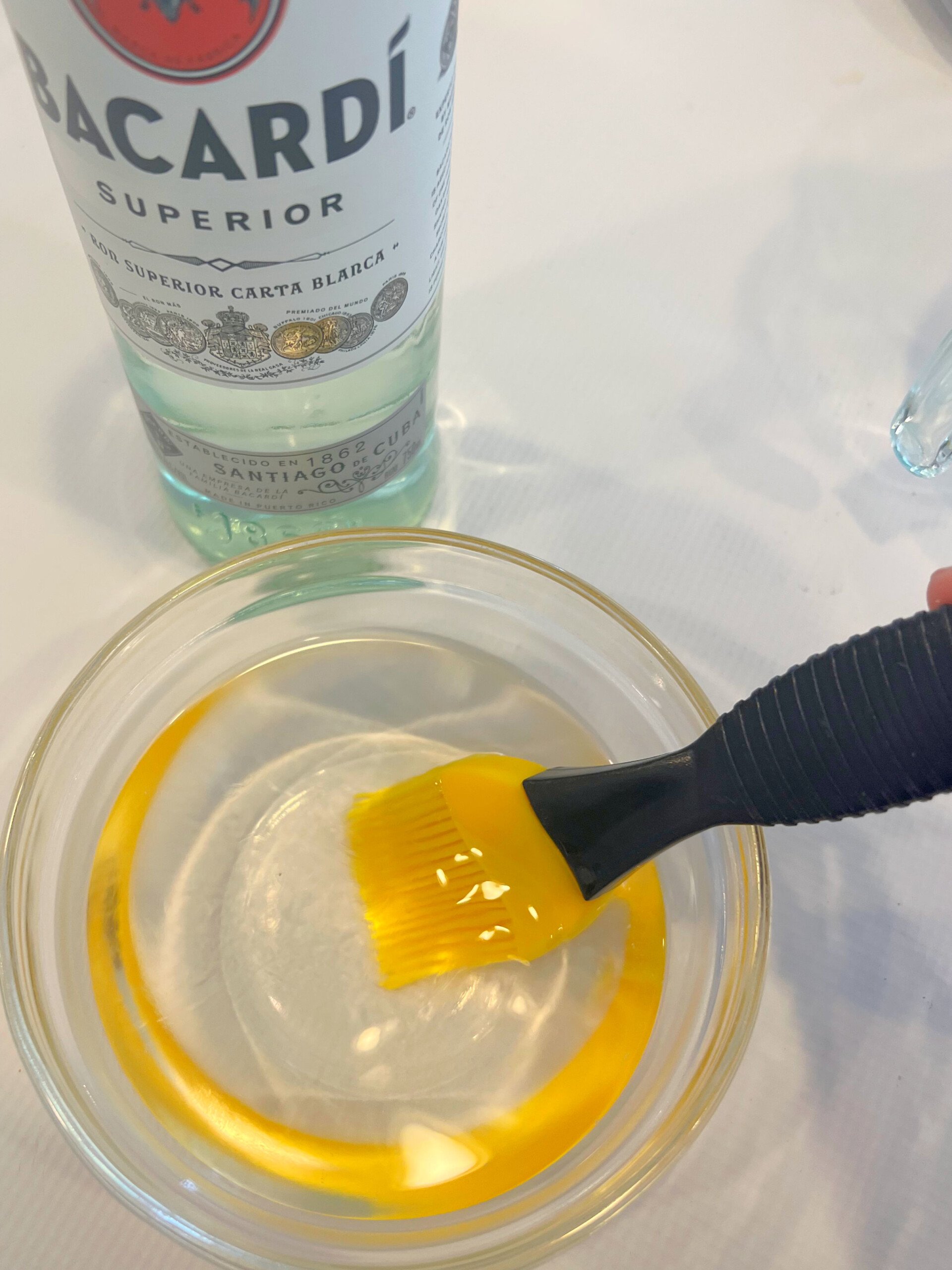 Rum simple syrup in a bowl with silicone pastry brush.