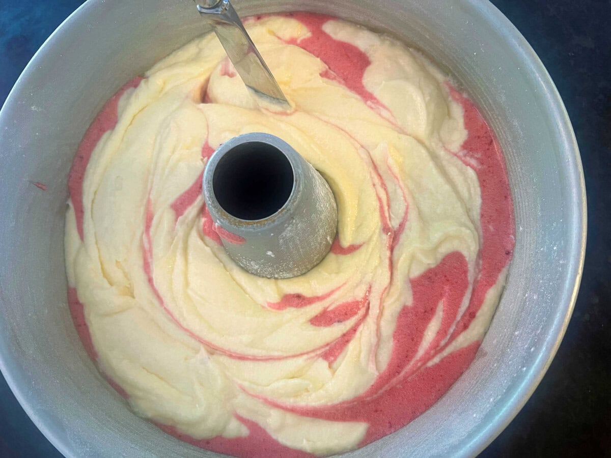 Lemon Raspberry Batter layered in the bundt cake pan, using knife to swirl.