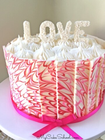 Pink and white marbled chocolate panel cake on a cake pedestal