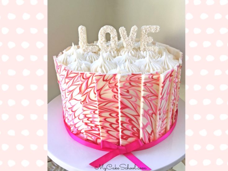 Pink and white marbled chocolate panel cake on a cake pedestal