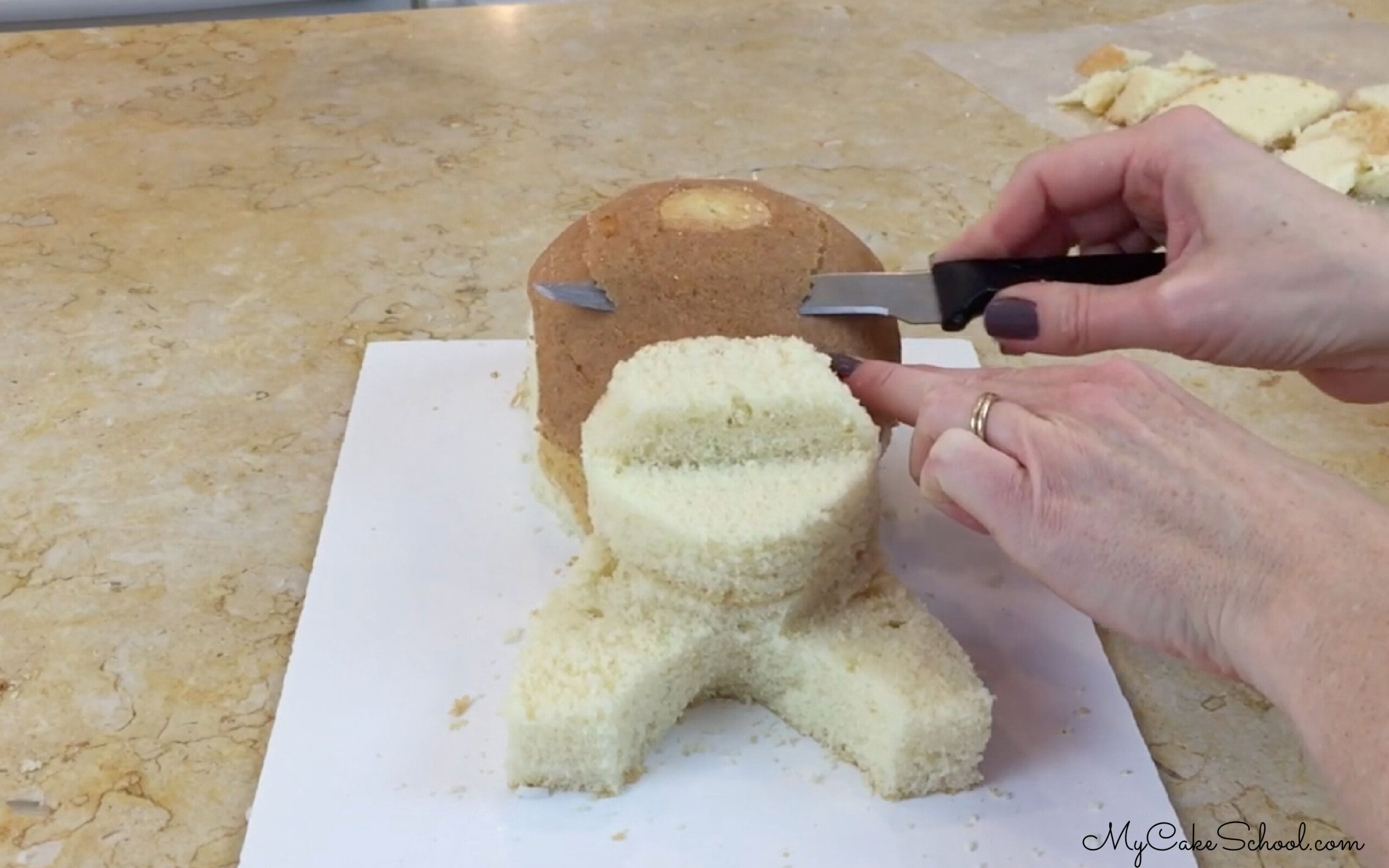 Carving the unfrosted cake layers for the puppy cake.