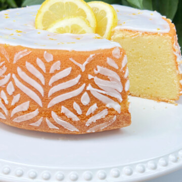 Sliced Lemon Pound Cake on a white pedestal with white stenciling around the sides.