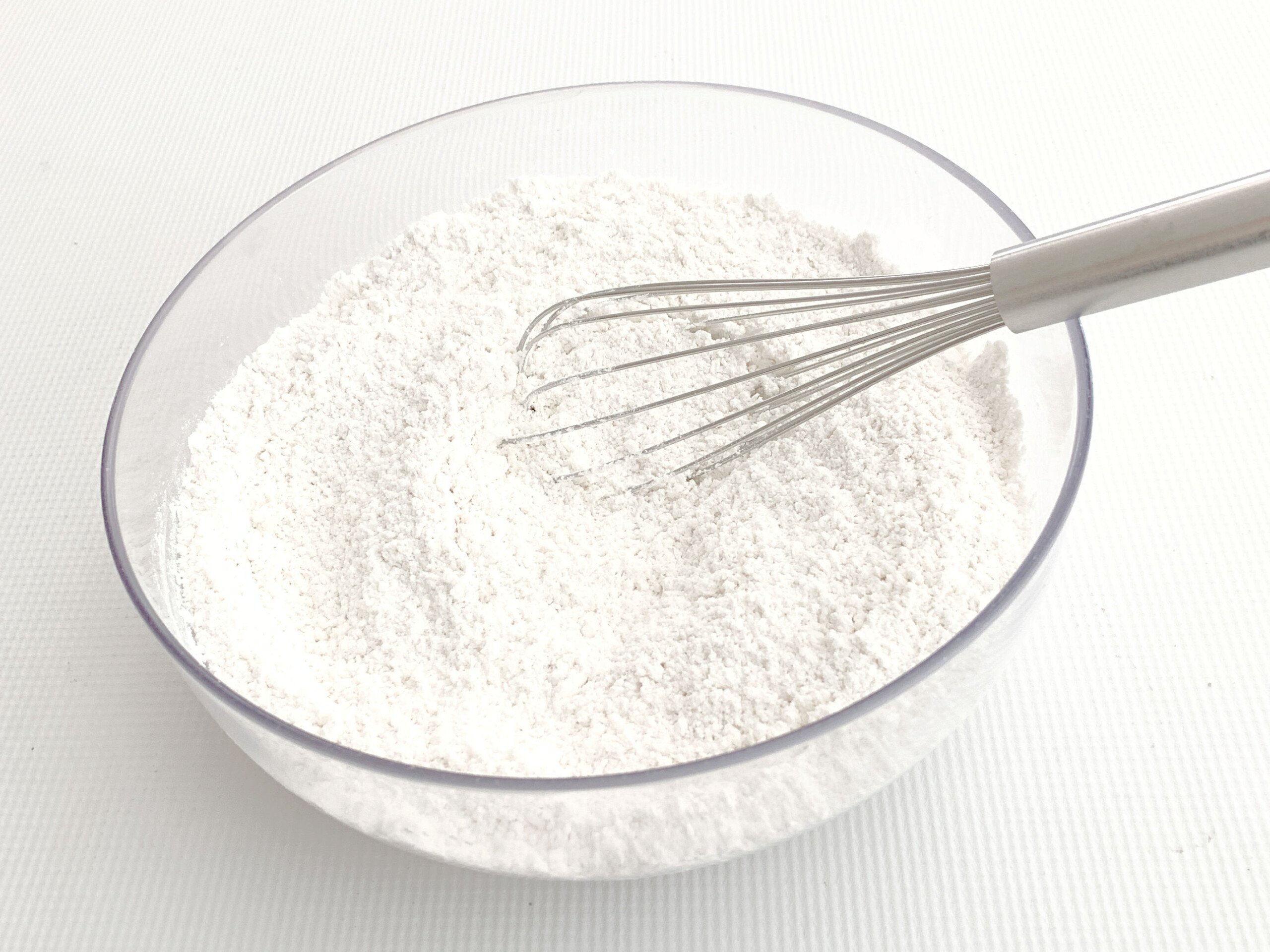 Dry Ingredients in a glass bowl with a whisk.