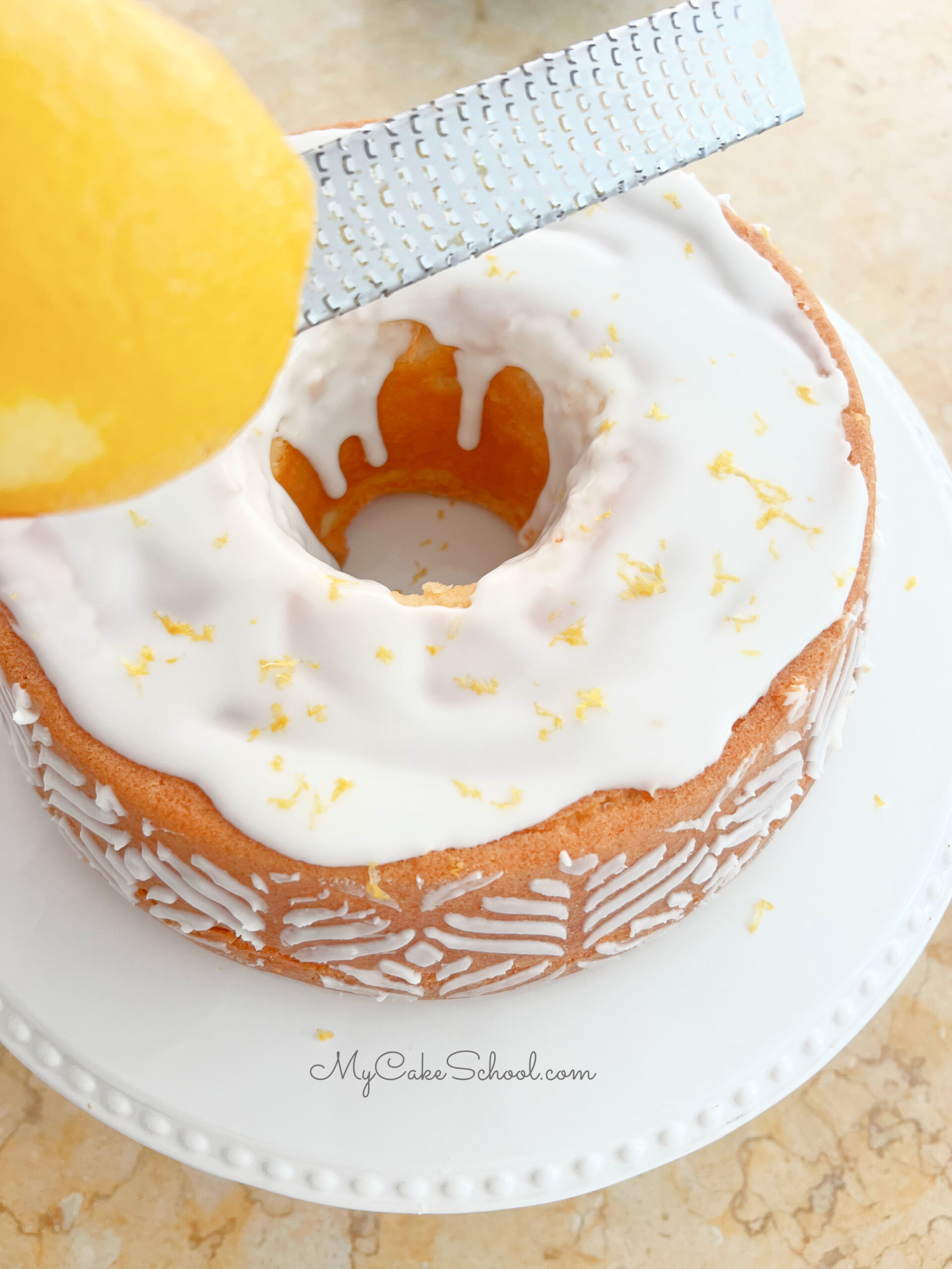 Adding lemon zest to the top of the cake for a final touch.