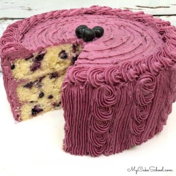 Lemon Blueberry Cake, sliced, on a cake pedestal.