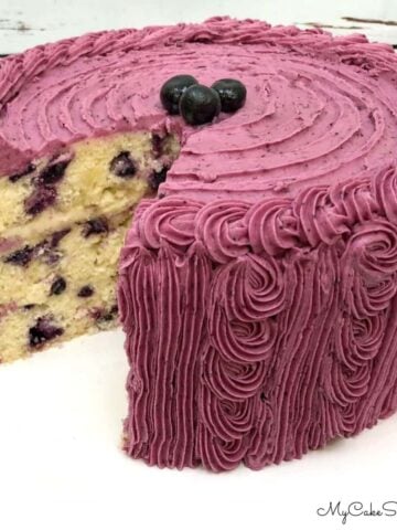 Lemon Blueberry Cake, sliced, on a cake pedestal.