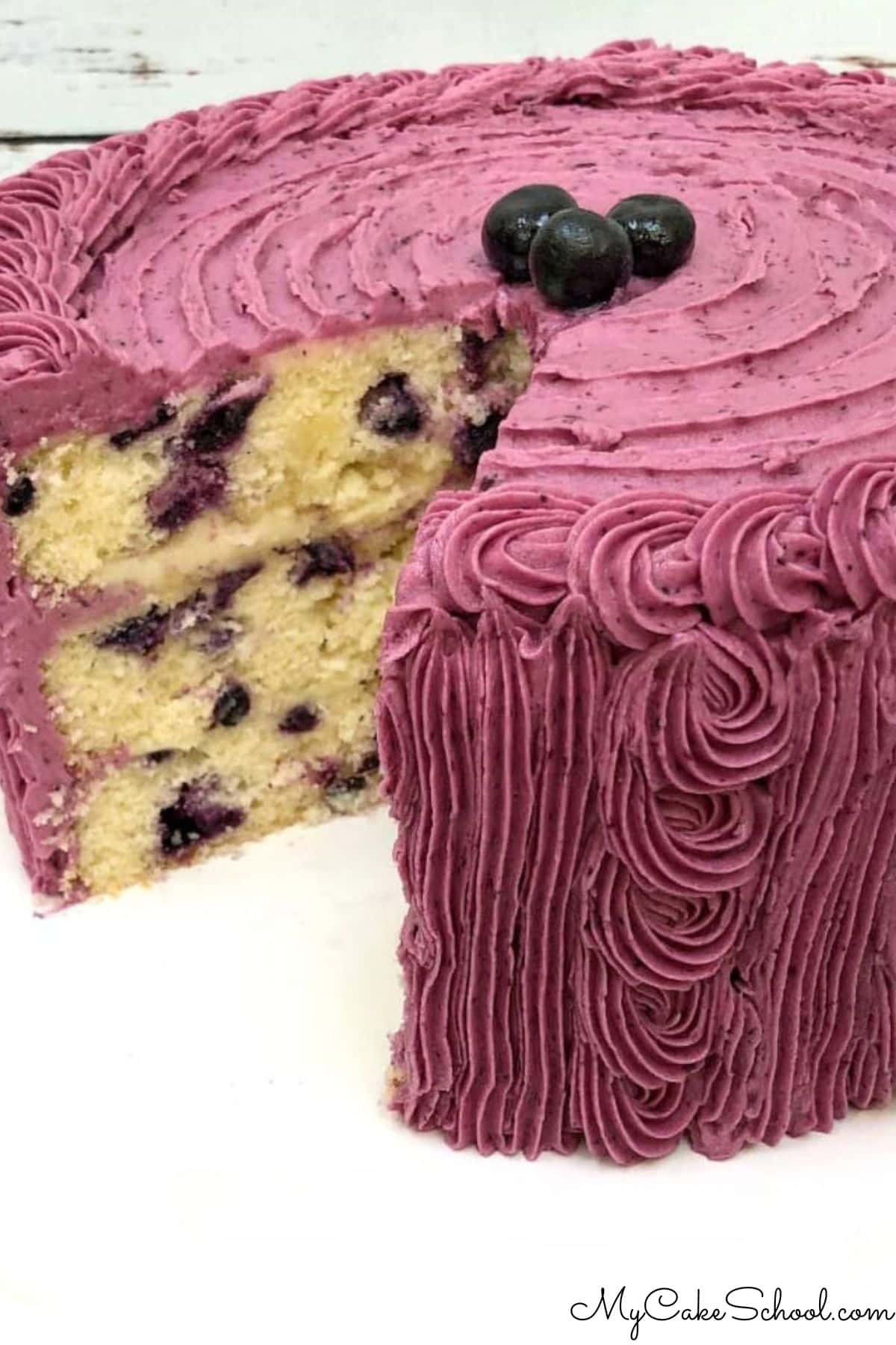 Lemon Blueberry Cake, sliced, on a cake pedestal.