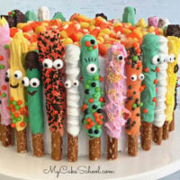 Colorful Pretzel Rods, decorated as monsters, wrapped around the sides of a cake.