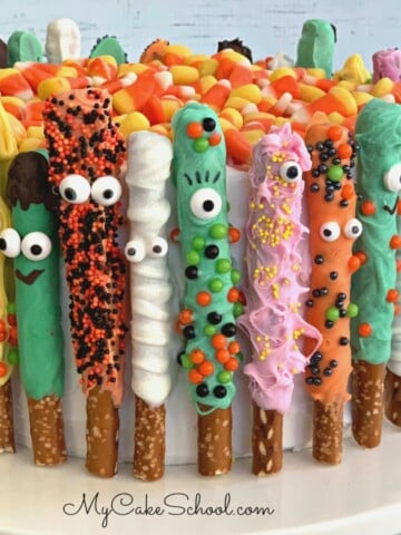 Colorful Pretzel Rods, decorated as monsters, wrapped around the sides of a cake.