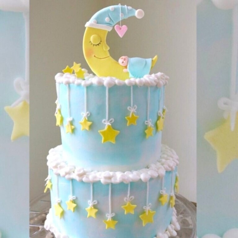 Moon and Stars themed Baby Shower Cake, on a cake pedestal. Light blue tiered cake with topper featuring baby sleeping on a crescent moon.