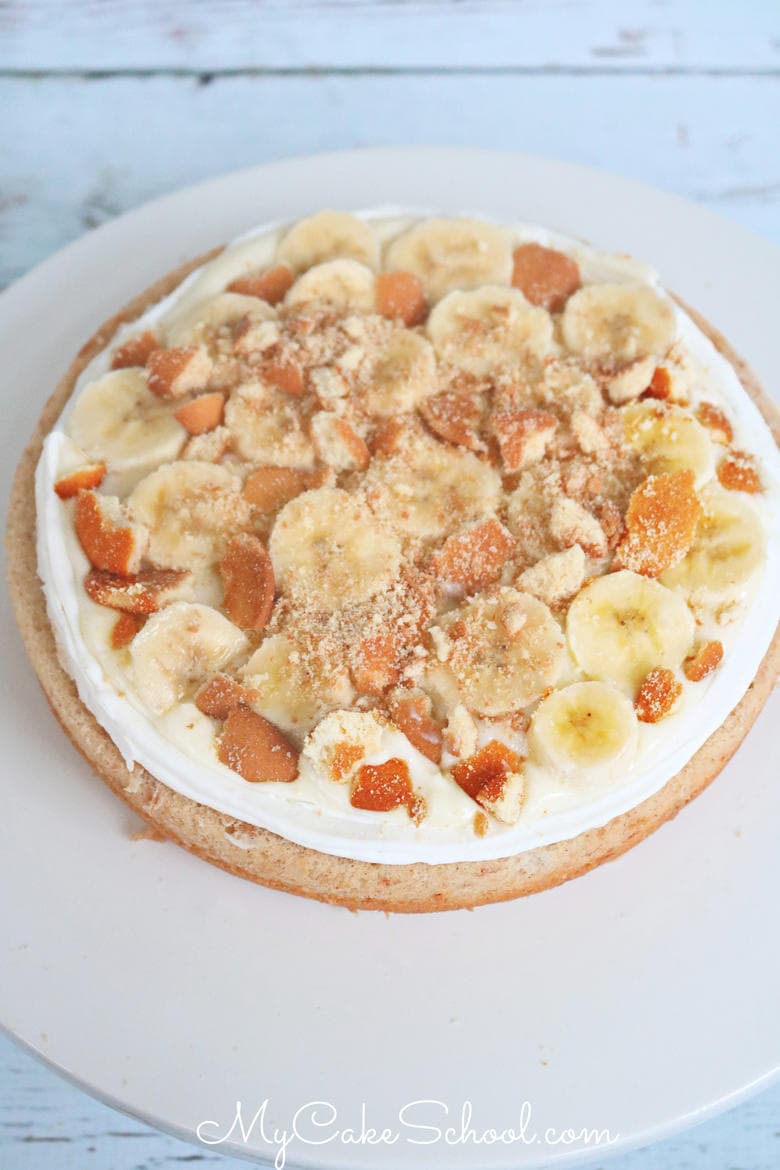 This Banana Pudding Cake recipe from scratch is an amazing combination of banana cake, crushed Nilla wafers, sliced bananas, and frosted with cream cheese frosting.