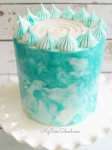 Blue and white marbled buttercream cake on white pedestal