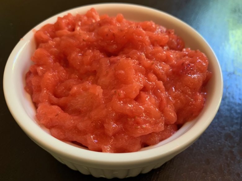 Cooked Strawberry Filling in a white glass bowl. We love to use this in our strawberry sour cream cake recipe!