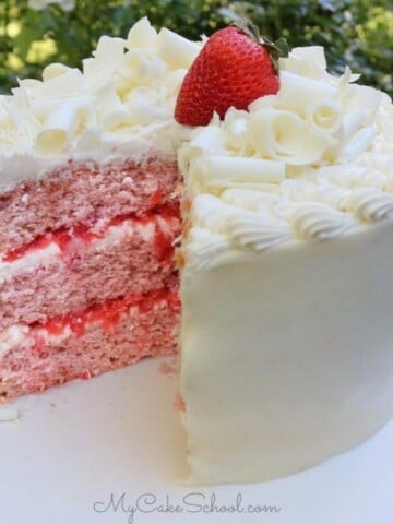 Strawberry Sour Cream Cake with White Chocolate Frosting, topped with white chocolate curls and a strawberry.