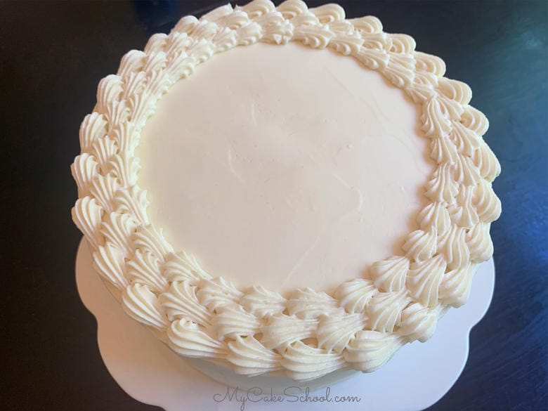 The top view of our Strawberry Sour Cream Cake, frosted with white chocolate frosting, and decorated with three rows of shell borders.