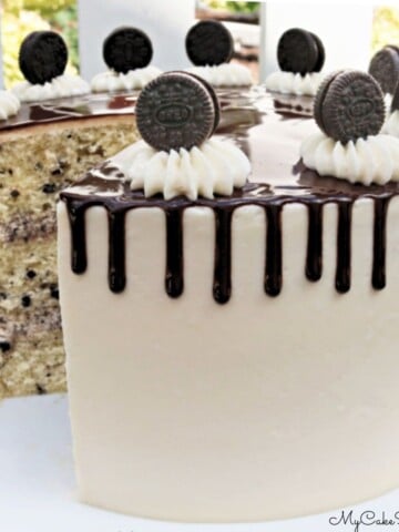 Sliced Cookies and Cream Cake on a white pedestal with a chocolate drip.