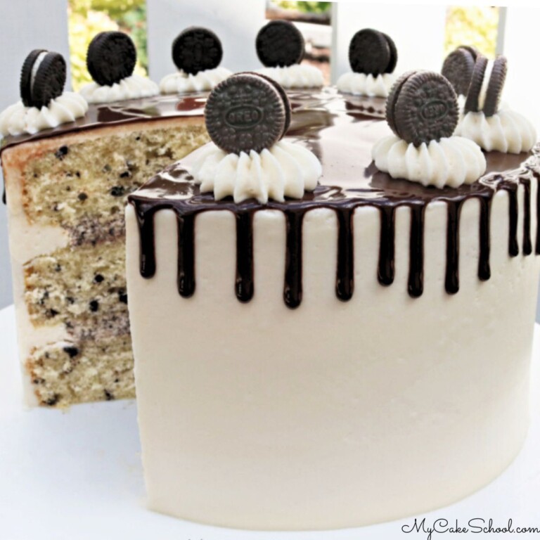 Sliced Cookies and Cream Cake on a white pedestal with a chocolate drip.