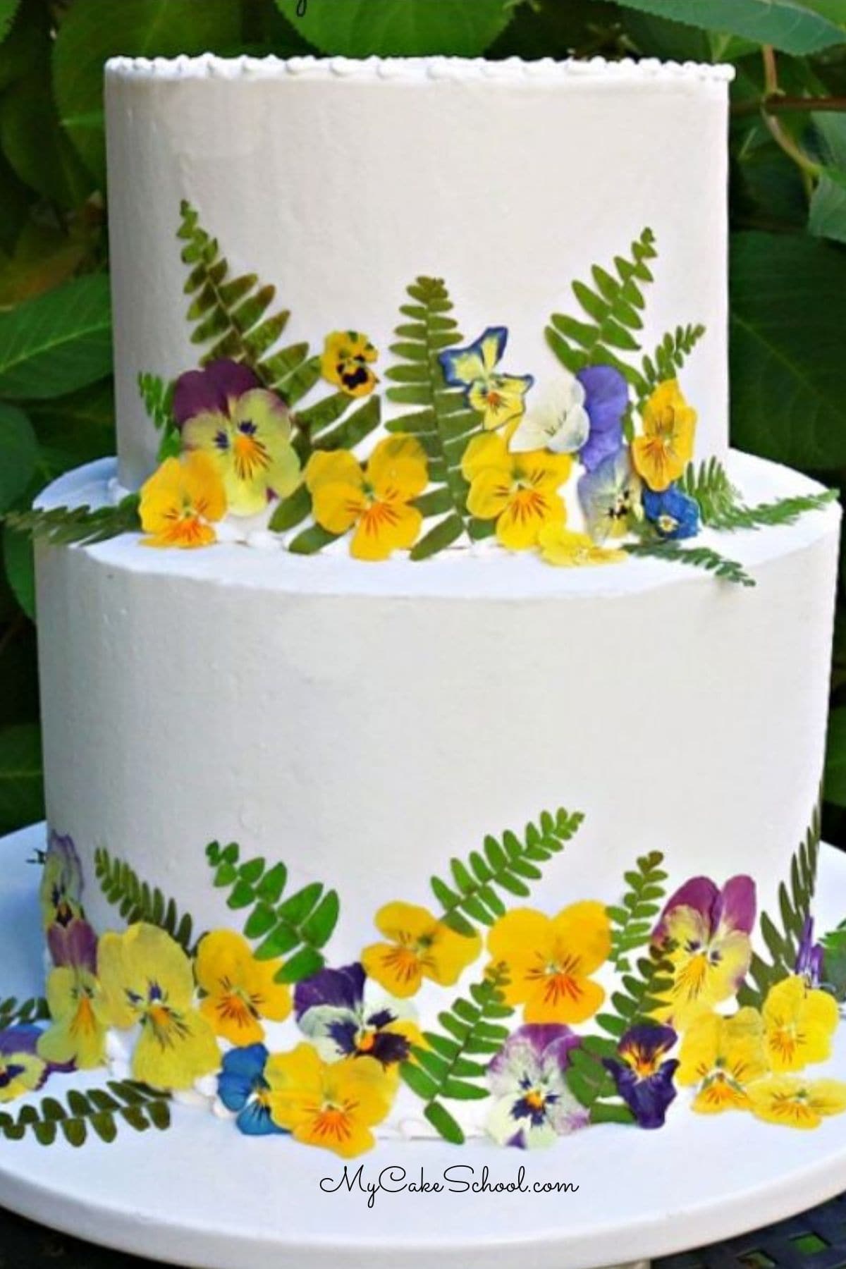 Beautiful, elegant pressed flowers and cake decorating Pressed Flowers cake on a pedestal.