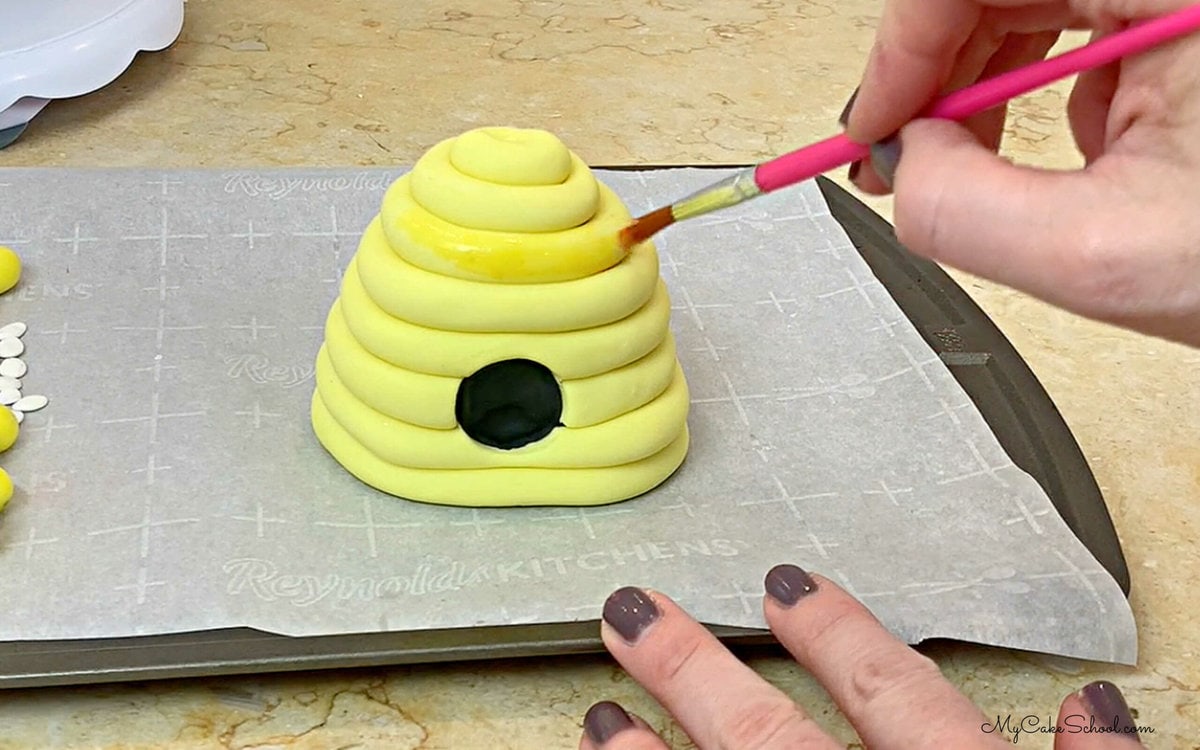 Painting the yellow beehive with a mix of coloring gel and vodka to make the shade of yellow a better match for the yellow candy coating wrap.