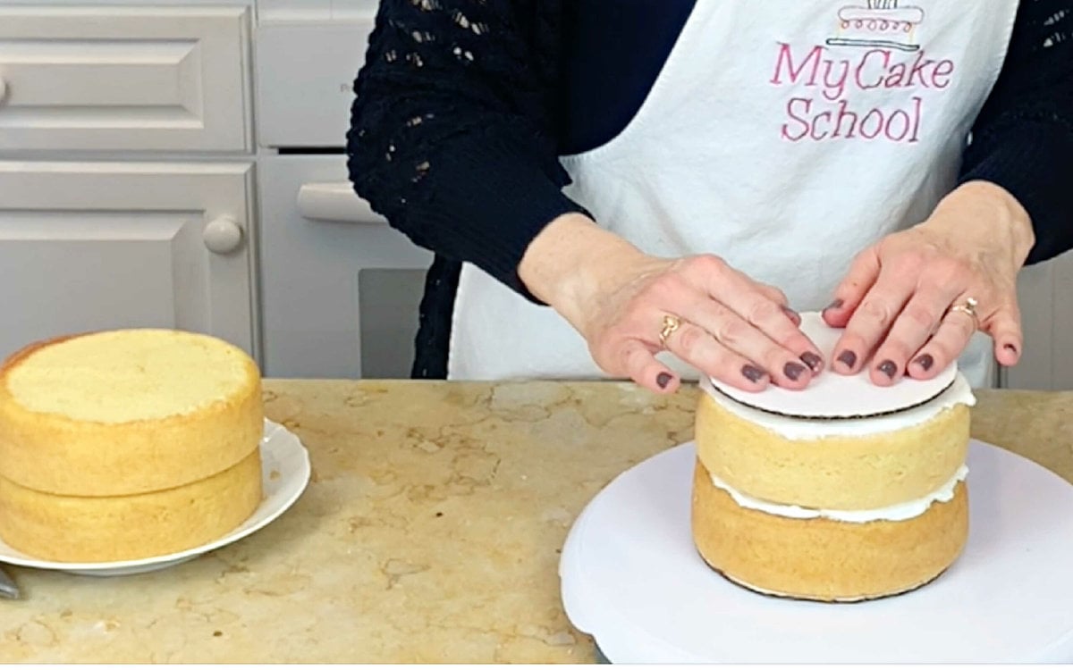 Placing cake cardboard over 4 bubble tea straws in bottom two layers of my double barrel cake.