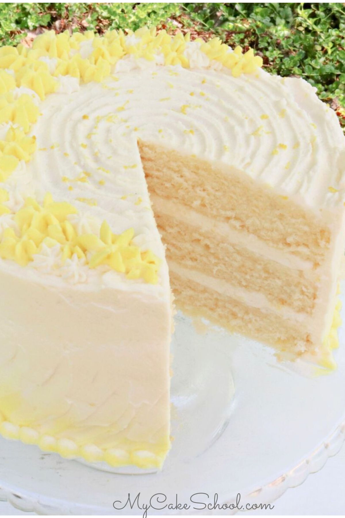 Lemon Buttermilk Cake, sliced, on a glass pedestal.