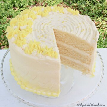 Lemon Buttermilk Cake, sliced, on a glass pedestal.