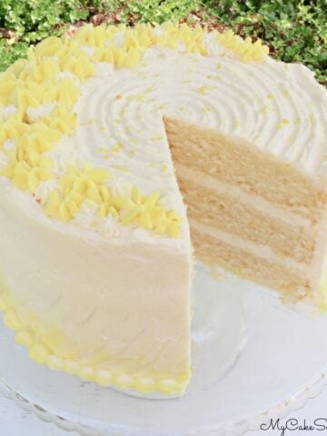 Lemon Buttermilk Cake, sliced, on a glass pedestal.
