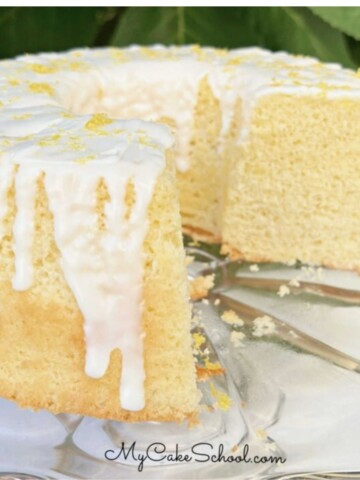 Lemon Chiffon Cake, sliced and glazed, on a glass pedestal.