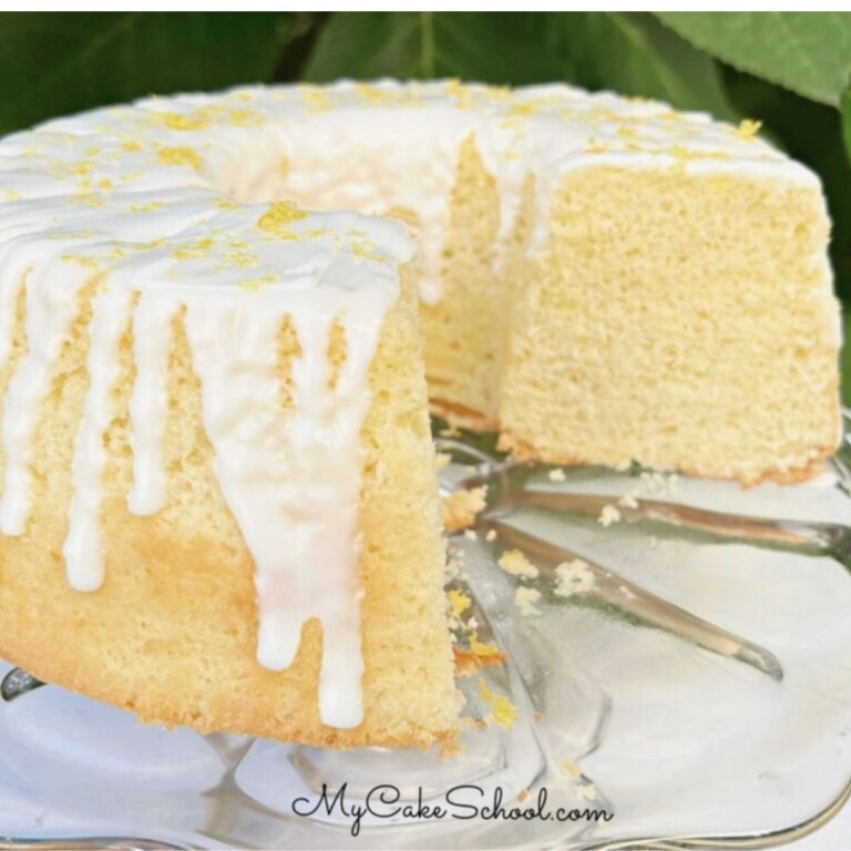 Lemon Chiffon Cake, sliced and glazed, on a glass pedestal.