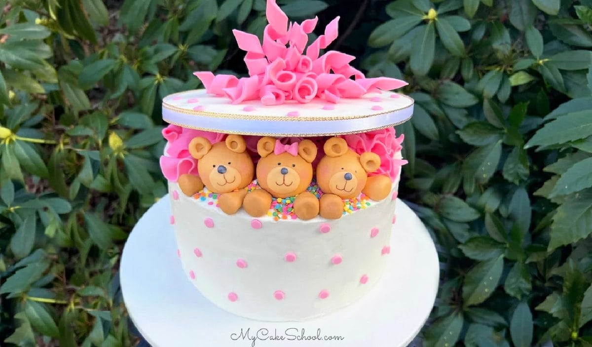 Teddy Bear Gift Cake with three fondant bears. Cake on white pedestal.