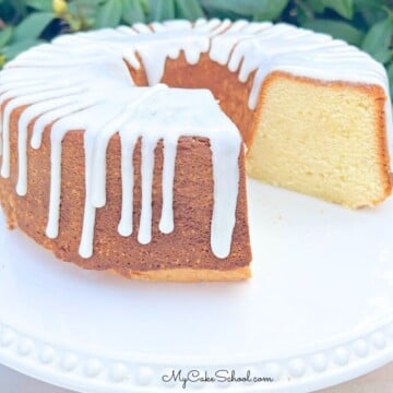 Sour cream pound cake, sliced, glazed, and on a white pedestal.