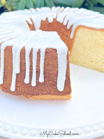 Sour cream pound cake, sliced, glazed, and on a white pedestal.