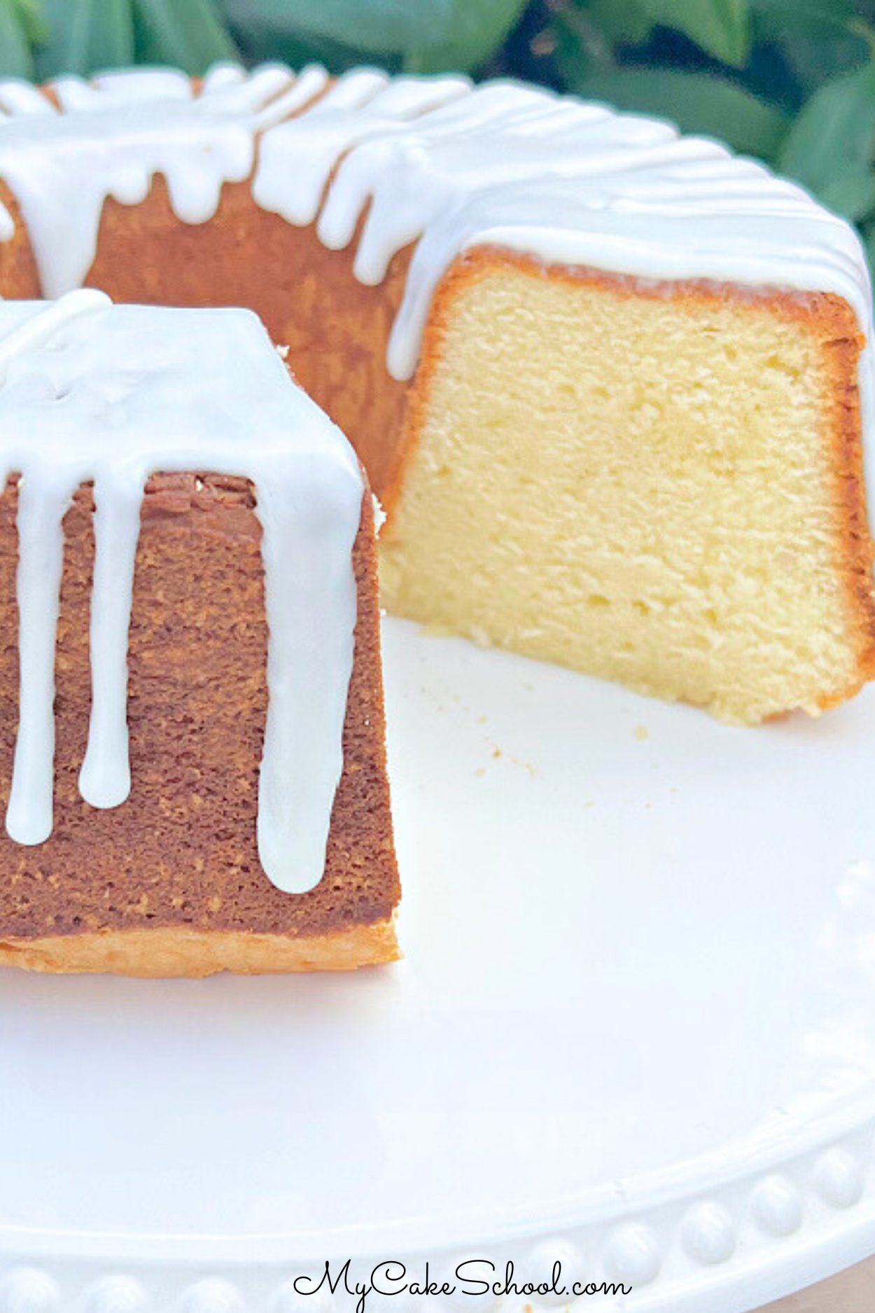 Glazed Sour Cream Pound Cake, sliced, on a white cake pedestal.