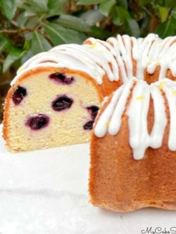 Lemon Blueberry Pound Cake, sliced, on a cake pedestal.